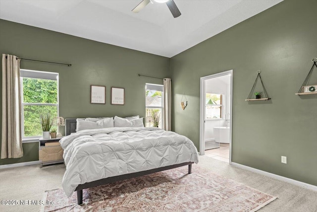 bedroom with light carpet, multiple windows, baseboards, and ensuite bathroom