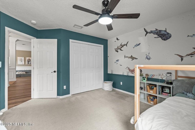 bedroom with a closet, carpet floors, a textured ceiling, ceiling fan, and baseboards