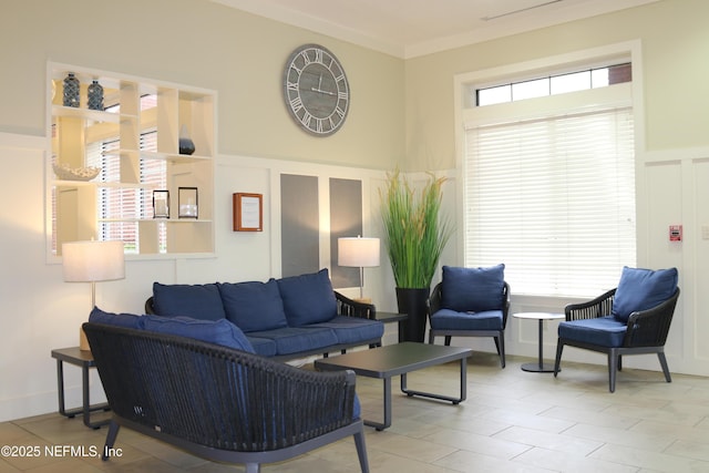 living room with a decorative wall, a wainscoted wall, and ornamental molding