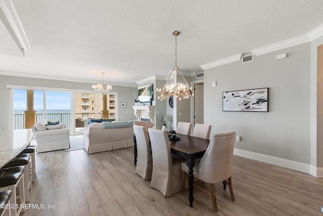 932 1st St N Unit 902, Jacksonville Beach, FL 32250 - dining area featuring a chandelier, light wood-style flooring, baseboards, crown molding, and a textured ceiling