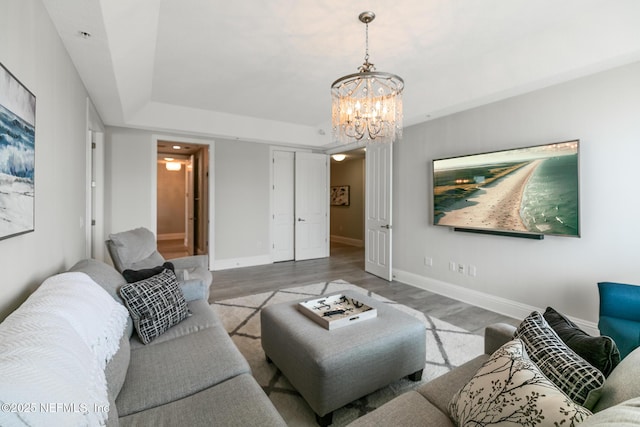 932 1st St N Unit 902, Jacksonville Beach, FL 32250 - living area featuring a chandelier, light wood-style floors, baseboards, and a tray ceiling