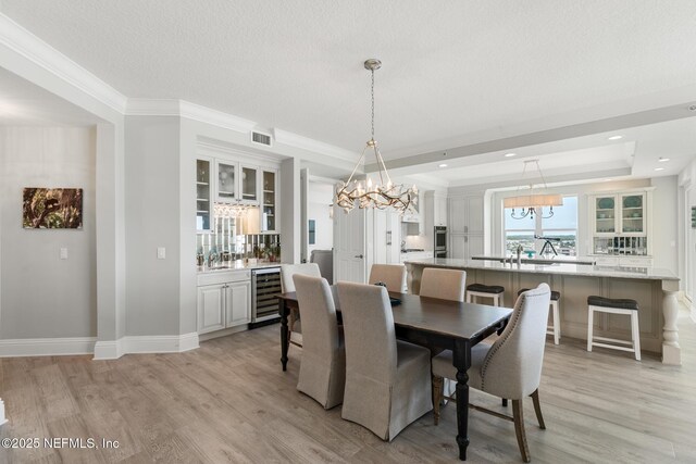 932 1st St N Unit 902, Jacksonville Beach, FL 32250 - dining space with wine cooler, a chandelier, light wood-style flooring, a tray ceiling, and baseboards