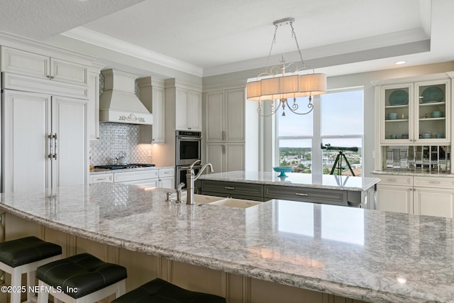 932 1st St N Unit 902, Jacksonville Beach, FL 32250 - kitchen with custom exhaust hood, a sink, a kitchen island, stainless steel appliances, and backsplash