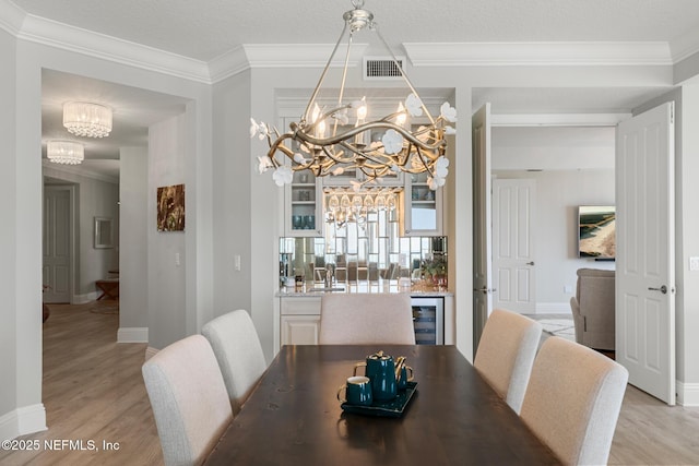 932 1st St N Unit 902, Jacksonville Beach, FL 32250 - dining space featuring a chandelier, light wood-style floors, baseboards, wine cooler, and crown molding