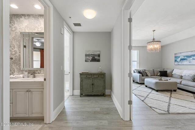 932 1st St N Unit 902, Jacksonville Beach, FL 32250 - hallway with light wood finished floors, a chandelier, baseboards, and a sink