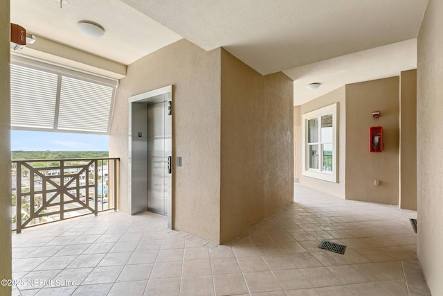 932 1st St N Unit 902, Jacksonville Beach, FL 32250 - hallway featuring a textured wall, elevator, and light tile patterned floors