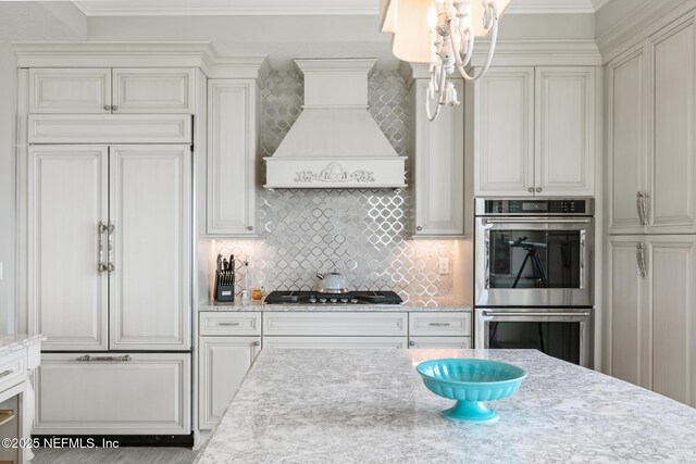 932 1st St N Unit 902, Jacksonville Beach, FL 32250 - kitchen with appliances with stainless steel finishes, custom exhaust hood, backsplash, a chandelier, and crown molding