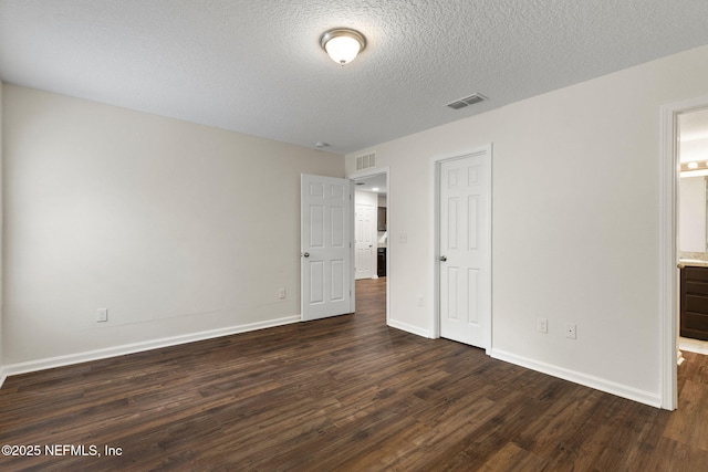 1343 Pangola Dr, Jacksonville, FL 32205 - unfurnished bedroom with dark wood-style flooring, a textured ceiling, and connected bathroom
