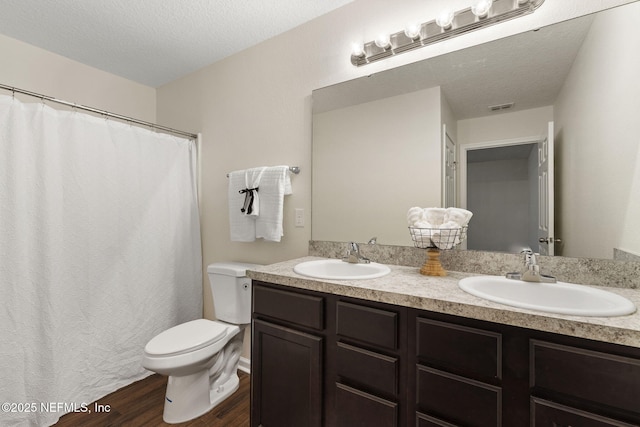 1343 Pangola Dr, Jacksonville, FL 32205 - full bathroom with double vanity, wood finished floors, and a textured ceiling