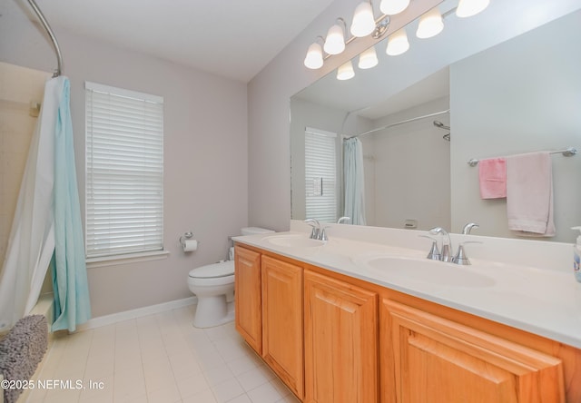 bathroom featuring toilet, double vanity, tile patterned floors, and baseboards