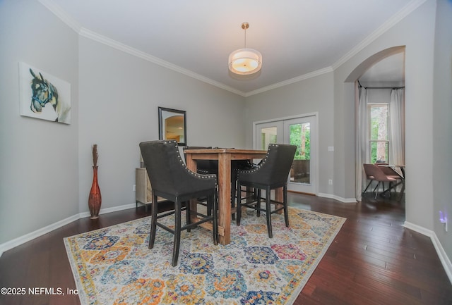 dining room featuring arched walkways, ornamental molding, dark wood-type flooring, baseboards, and french doors