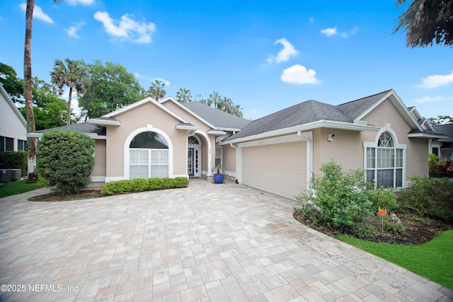 single story home featuring stucco siding, an attached garage, and decorative driveway