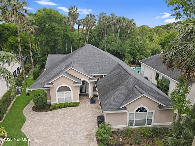 single story home featuring roof with shingles, stucco siding, decorative driveway, and central AC