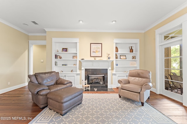 living room with built in features, wood finished floors, ornamental molding, and baseboards