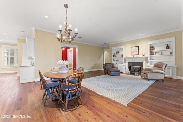 dining area featuring a chandelier, built in shelves, baseboards, hardwood / wood-style floors, and crown molding