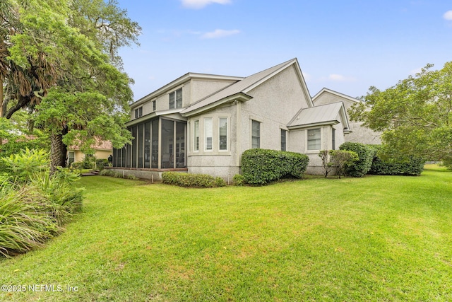 view of side of property with a sunroom, a yard, stucco siding, and metal roof