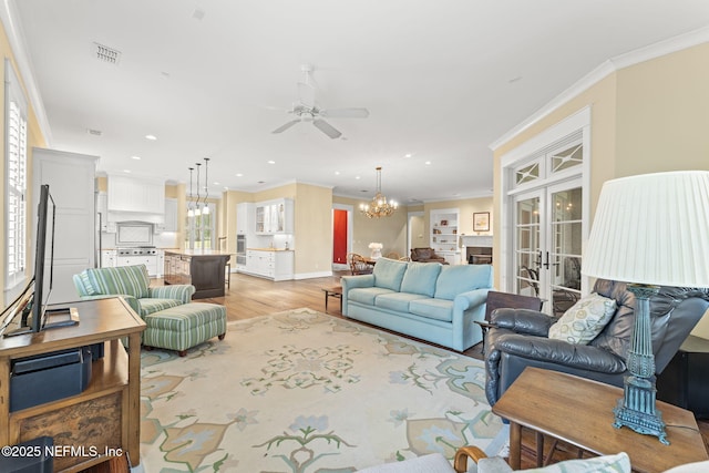 living room with a chandelier, ceiling fan, french doors, ornamental molding, and recessed lighting