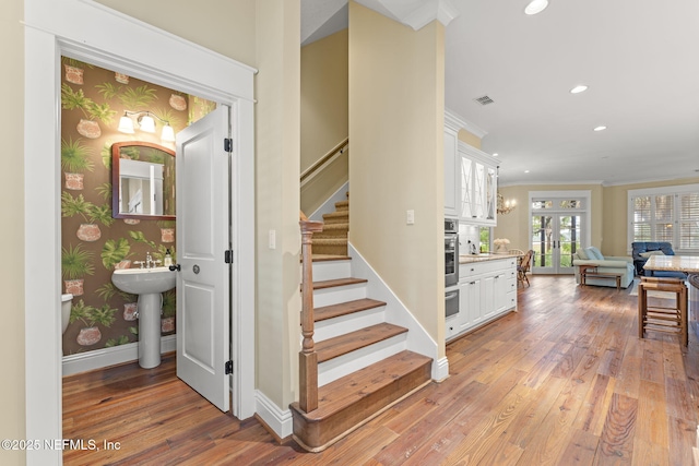 stairway featuring wood-type flooring, ornamental molding, baseboards, recessed lighting, and wallpapered walls