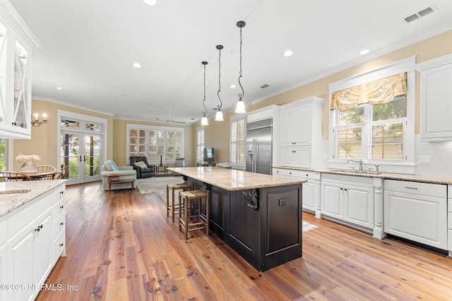kitchen featuring built in fridge, ornamental molding, light wood-type flooring, white cabinetry, and recessed lighting