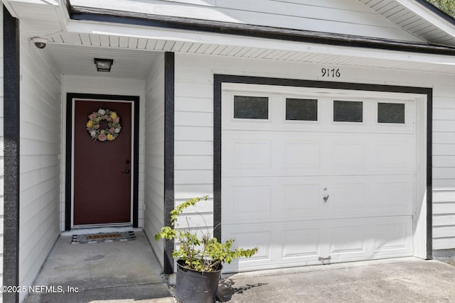entrance to property with a surveillance system, a garage, and driveway