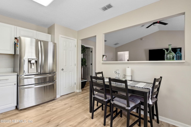 dining area with light wood finished floors, lofted ceiling, ceiling fan, and baseboards