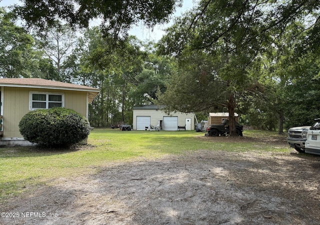 view of grassy yard with a garage, an outdoor structure, and a storage unit