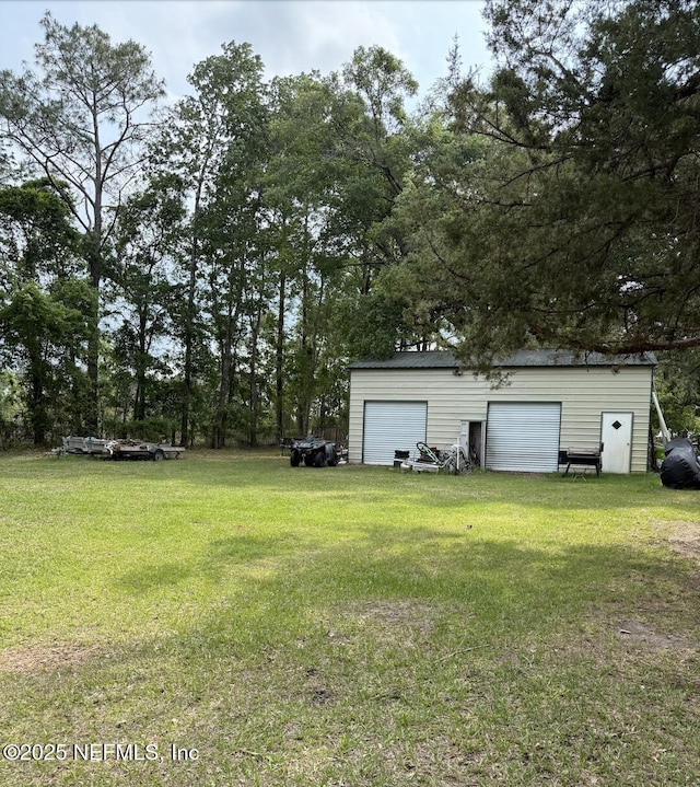 view of grassy yard featuring a detached garage and an outbuilding
