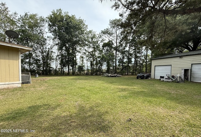 view of grassy yard with cooling unit and a garage