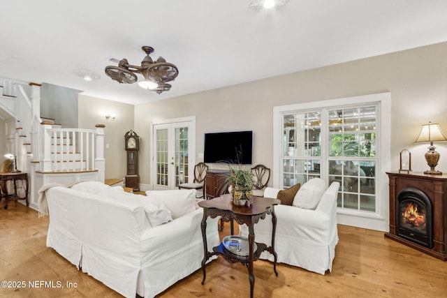 96448 Marsh Hen Rd, Fernandina Beach, FL 32034 - living room featuring stairway, light wood-style flooring, french doors, and a lit fireplace