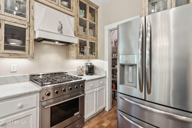 96448 Marsh Hen Rd, Fernandina Beach, FL 32034 - kitchen with appliances with stainless steel finishes, custom exhaust hood, brick flooring, glass insert cabinets, and light stone countertops