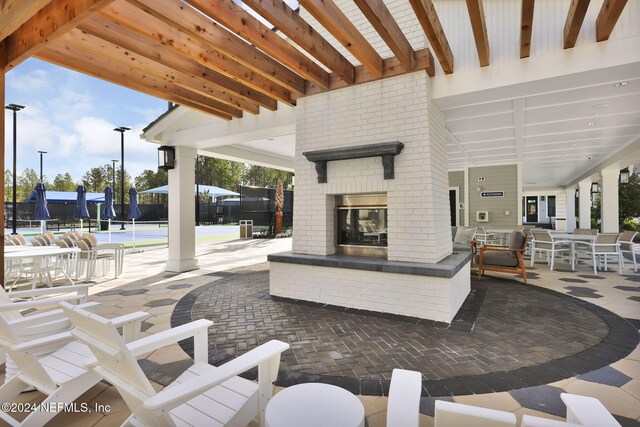 view of patio / terrace featuring an outdoor brick fireplace and fence