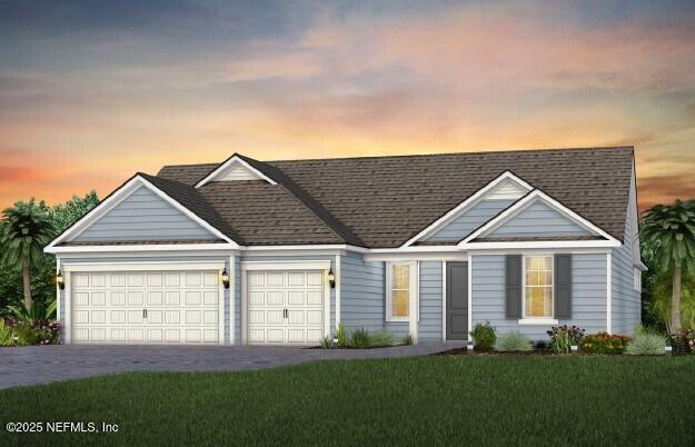view of front facade featuring an attached garage, driveway, a yard, and roof with shingles