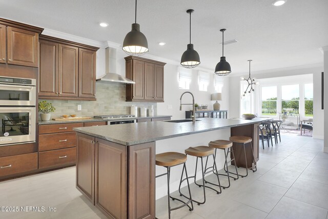 334 Continuum Loop, Yulee, FL 32097 - kitchen featuring a sink, wall chimney exhaust hood, stainless steel appliances, a kitchen island with sink, and tasteful backsplash