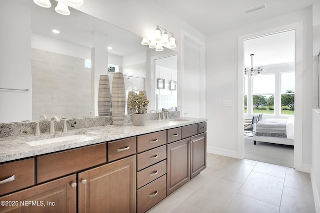 ensuite bathroom featuring a chandelier, double vanity, baseboards, tile patterned floors, and tiled shower