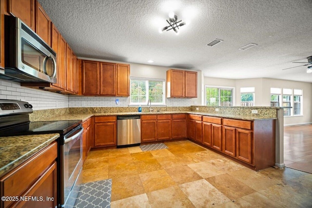 12198 Pebble Point Dr S, Jacksonville, FL 32218 - kitchen with stainless steel appliances, a sink, a peninsula, backsplash, and a textured ceiling