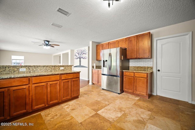 12198 Pebble Point Dr S, Jacksonville, FL 32218 - kitchen with stainless steel fridge with ice dispenser, a ceiling fan, decorative backsplash, brown cabinetry, and a textured ceiling