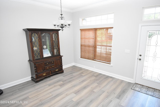 entryway with a chandelier, wood finished floors, crown molding, and baseboards