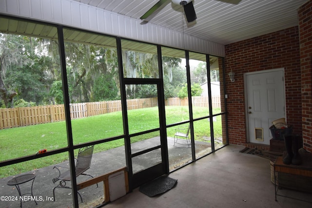 sunroom featuring a ceiling fan and a wood stove
