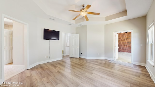 96069 Hidden Marsh Ln, Fernandina Beach, FL 32034 - unfurnished bedroom with a tray ceiling, light wood-type flooring, baseboards, a ceiling fan, and ensuite bath