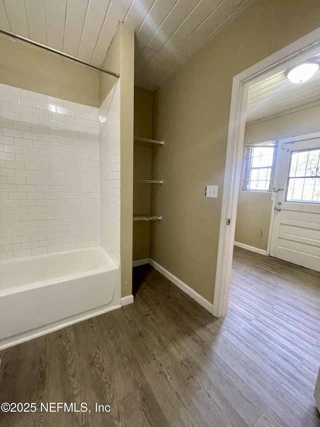 bathroom with wood finished floors, baseboards, and bathtub / shower combination