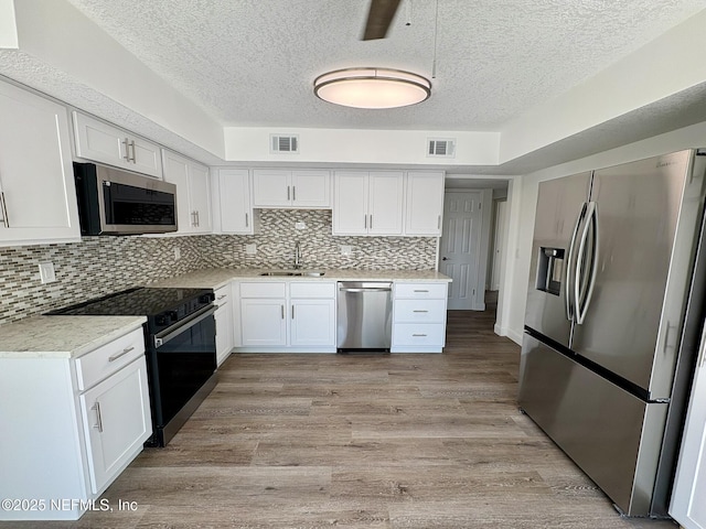 946 Cedar Ridge Ct, Orange Park, FL 32065 - kitchen featuring appliances with stainless steel finishes, a sink, white cabinets, a textured ceiling, and light countertops