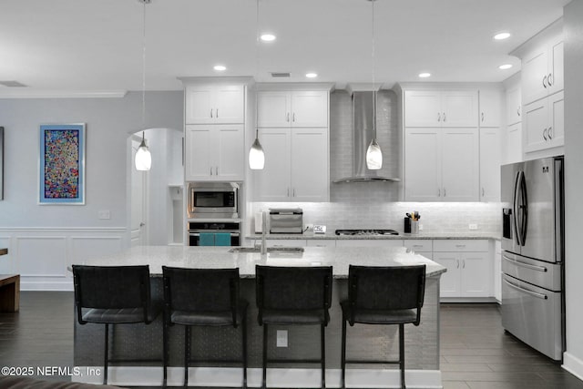 195 Manor Ln, Saint Johns, FL 32259 - kitchen featuring appliances with stainless steel finishes, wall chimney range hood, a sink, decorative backsplash, and white cabinets