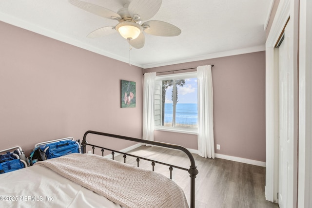 bedroom with wood finished floors, baseboards, crown molding, and ceiling fan