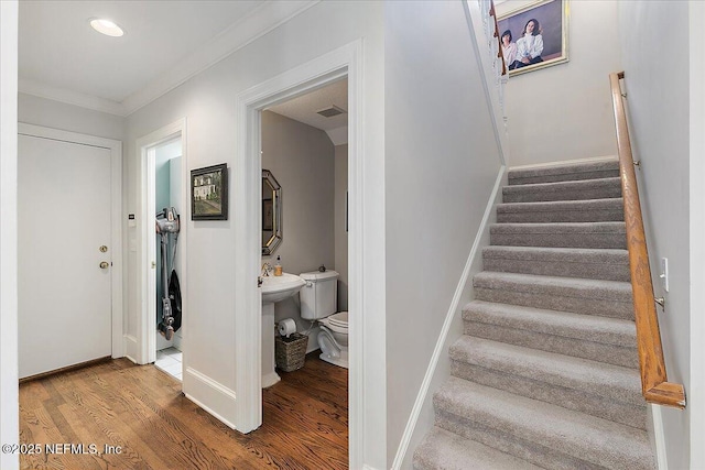 stairs featuring wood finished floors, crown molding, and baseboards