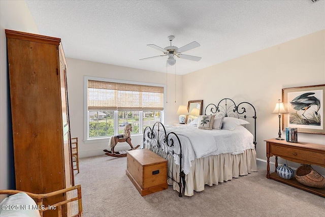 bedroom with light carpet, a ceiling fan, and a textured ceiling