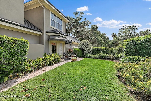 view of green lawn featuring a patio