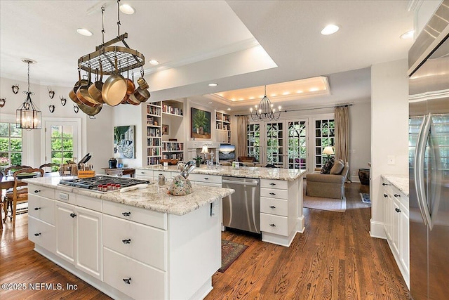 kitchen with stainless steel appliances, open floor plan, a chandelier, a kitchen island, and ornamental molding