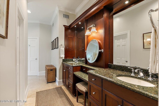 full bath featuring ornamental molding, two vanities, and baseboards