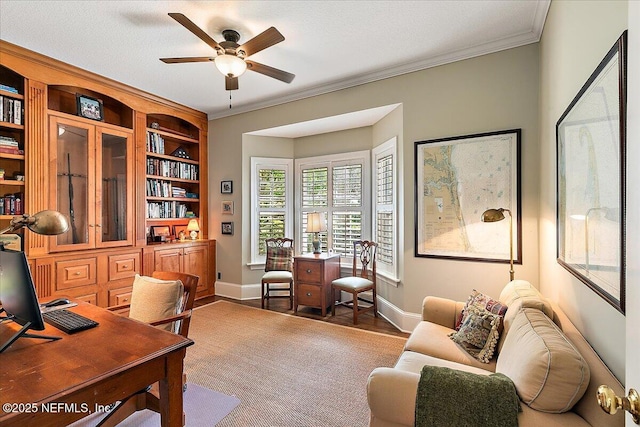 office space featuring a ceiling fan, ornamental molding, baseboards, and wood finished floors