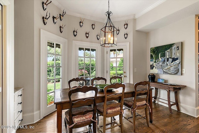 dining space with wood finished floors, baseboards, crown molding, and a chandelier
